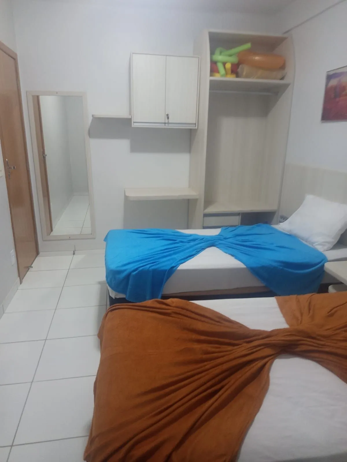 Quarto com camas arrumadas com mantas coloridas
